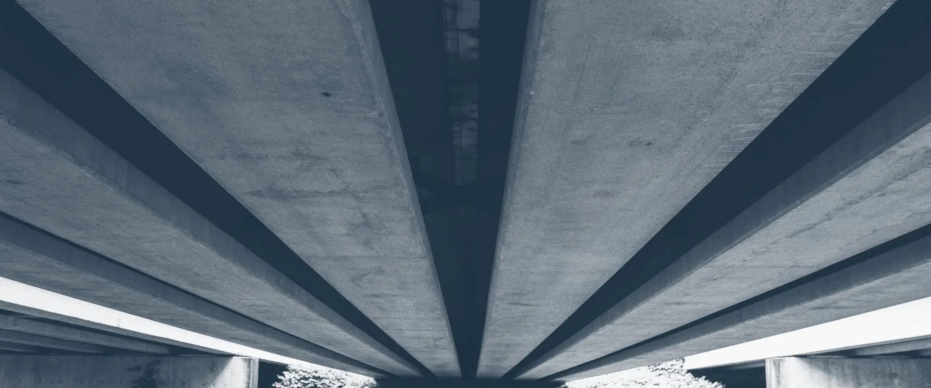 The underside of a concrete bridge, its beams radiating out from a single span.