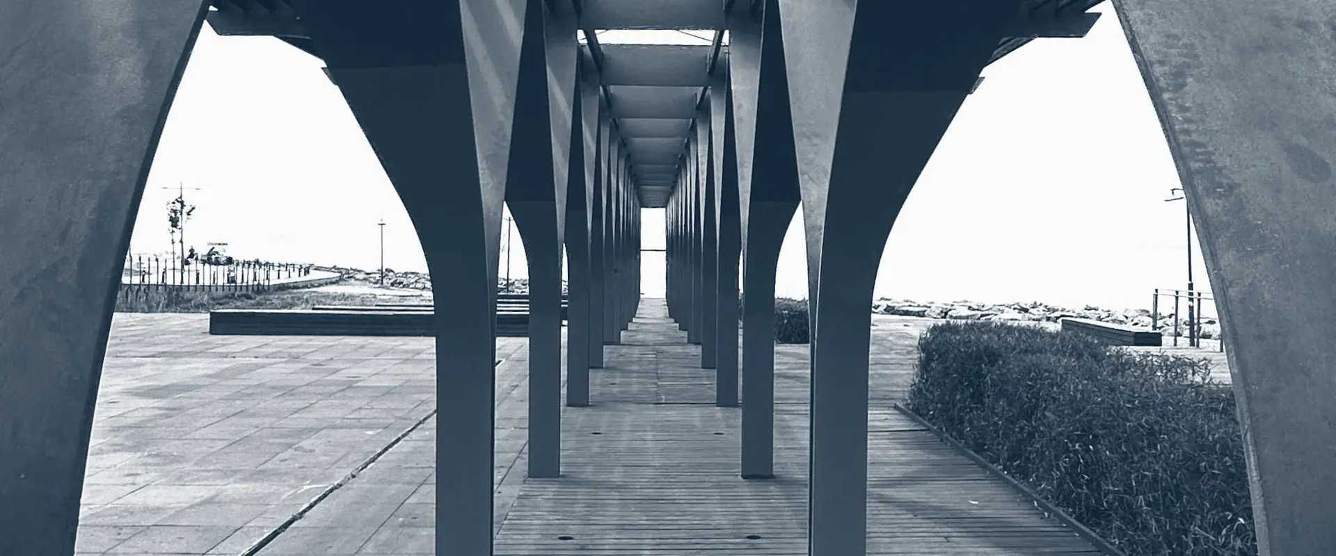 A long covered walkway carried on paired columns, running straight to a distant opening.