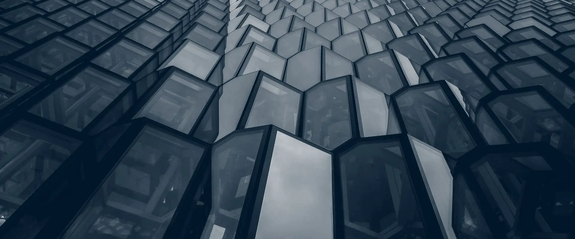 Angled glass panels on a building front, each facet catching the light differently.