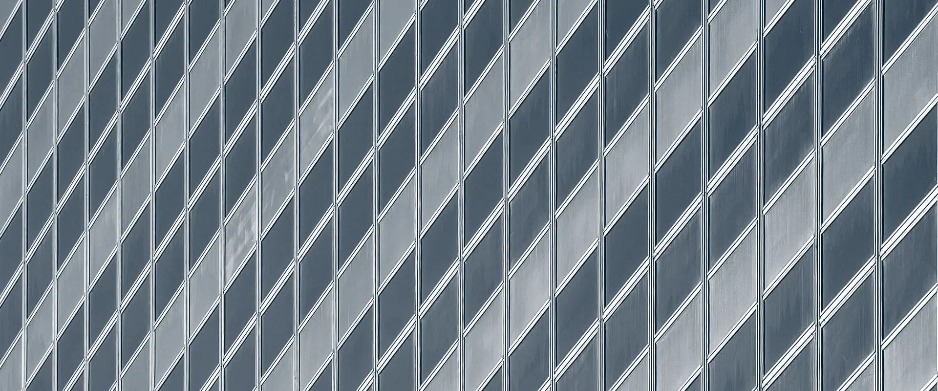 A tall glass facade seen at an angle, its windows forming a repeating diagonal grid.