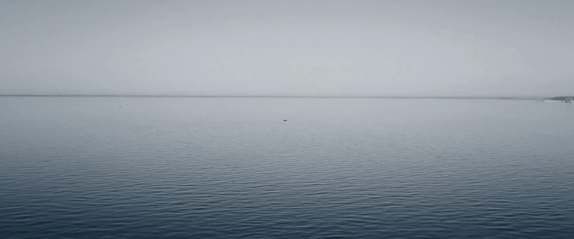 Open water meeting a pale sky at a single flat horizon line, nothing else in frame.