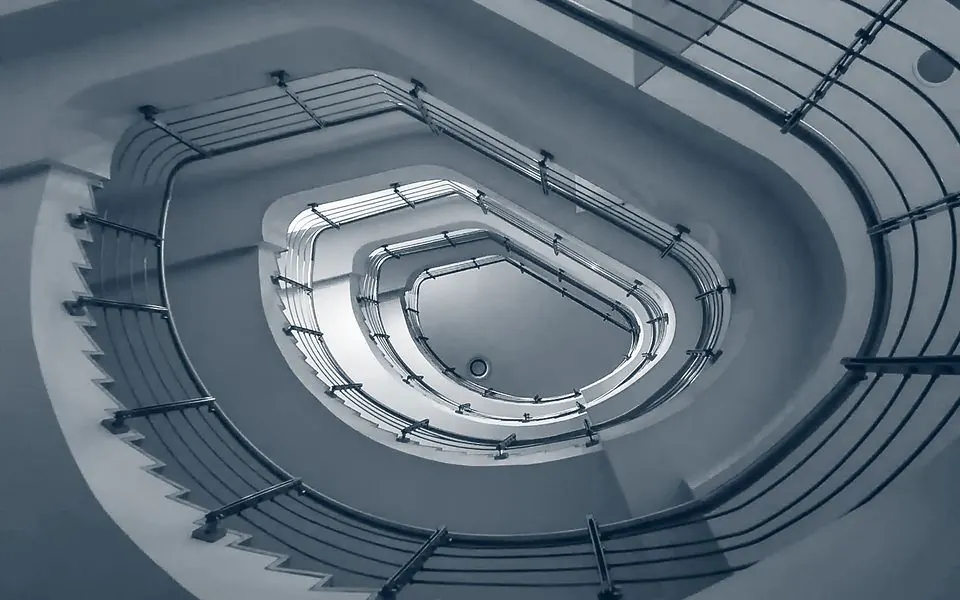 An oval stairwell seen from directly below, its flights coiling inward.