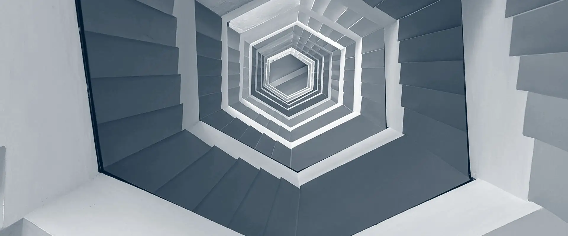 A hexagonal stairwell photographed from the bottom, each floor repeating inward toward the light.