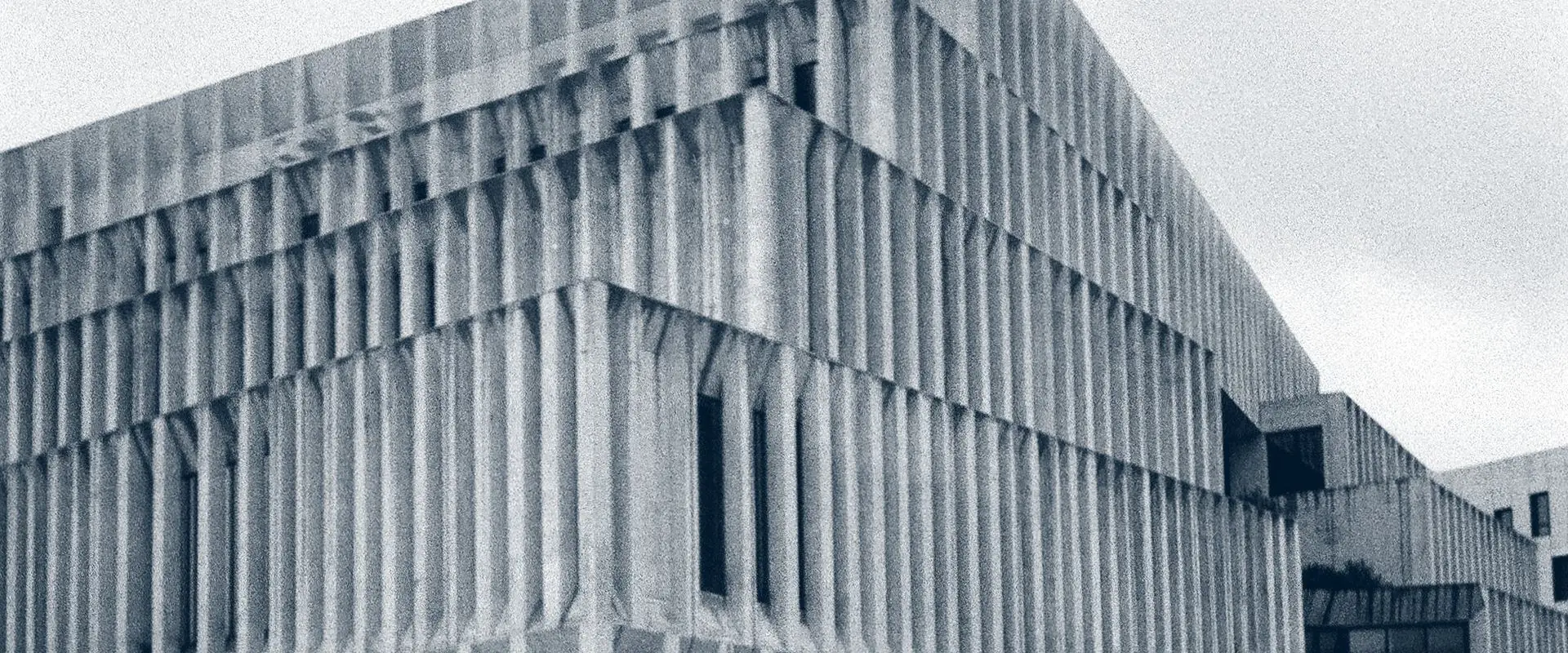 A concrete building front made of tall, closely spaced vertical fins, photographed straight on.