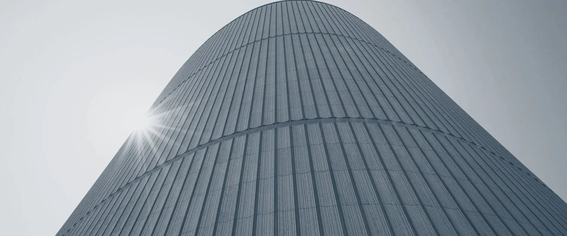A tower photographed from its base, every vertical line converging to one point at the top.